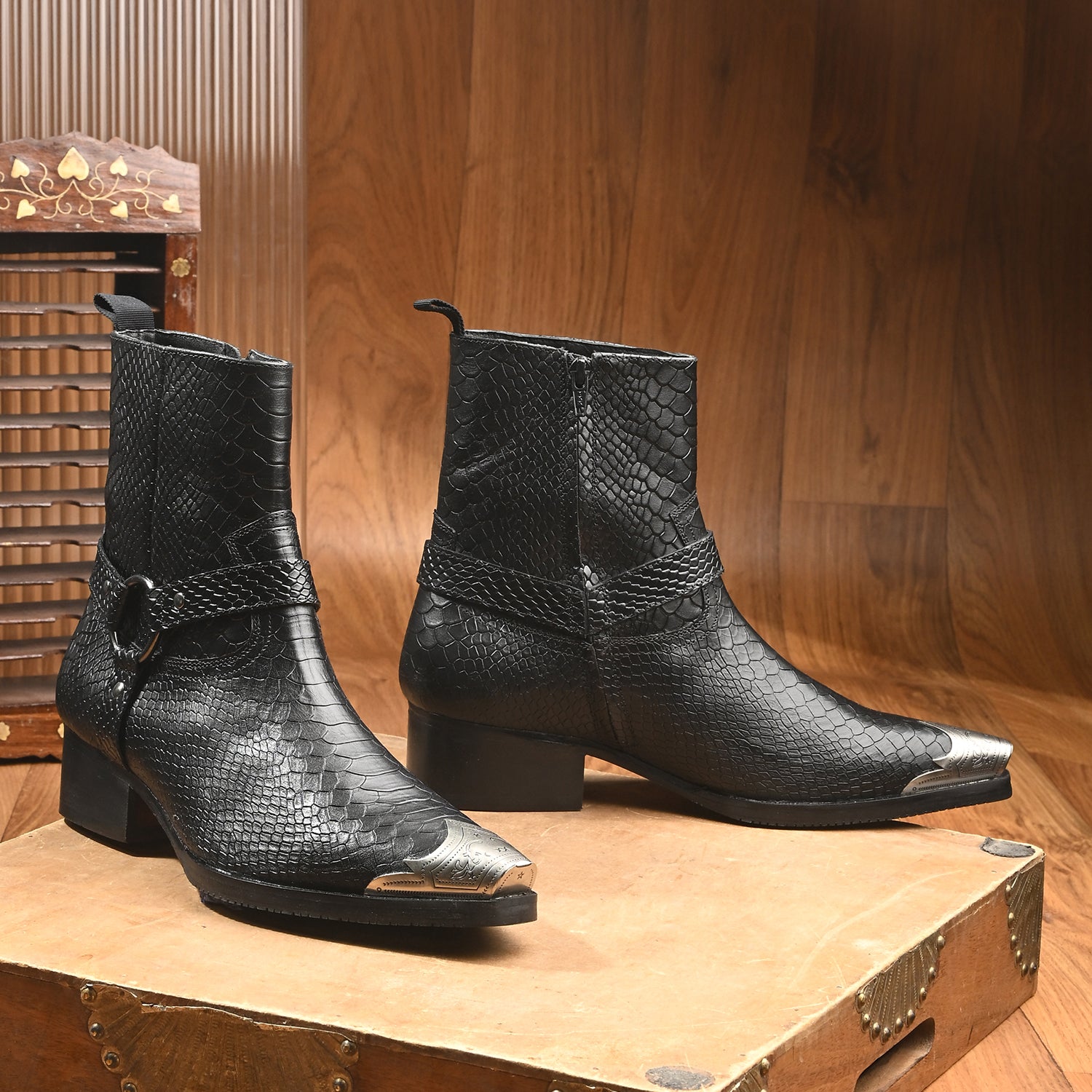 Black snakeskin-textured leather men’s Western ankle boots with harness strap and silver metal toe cap.