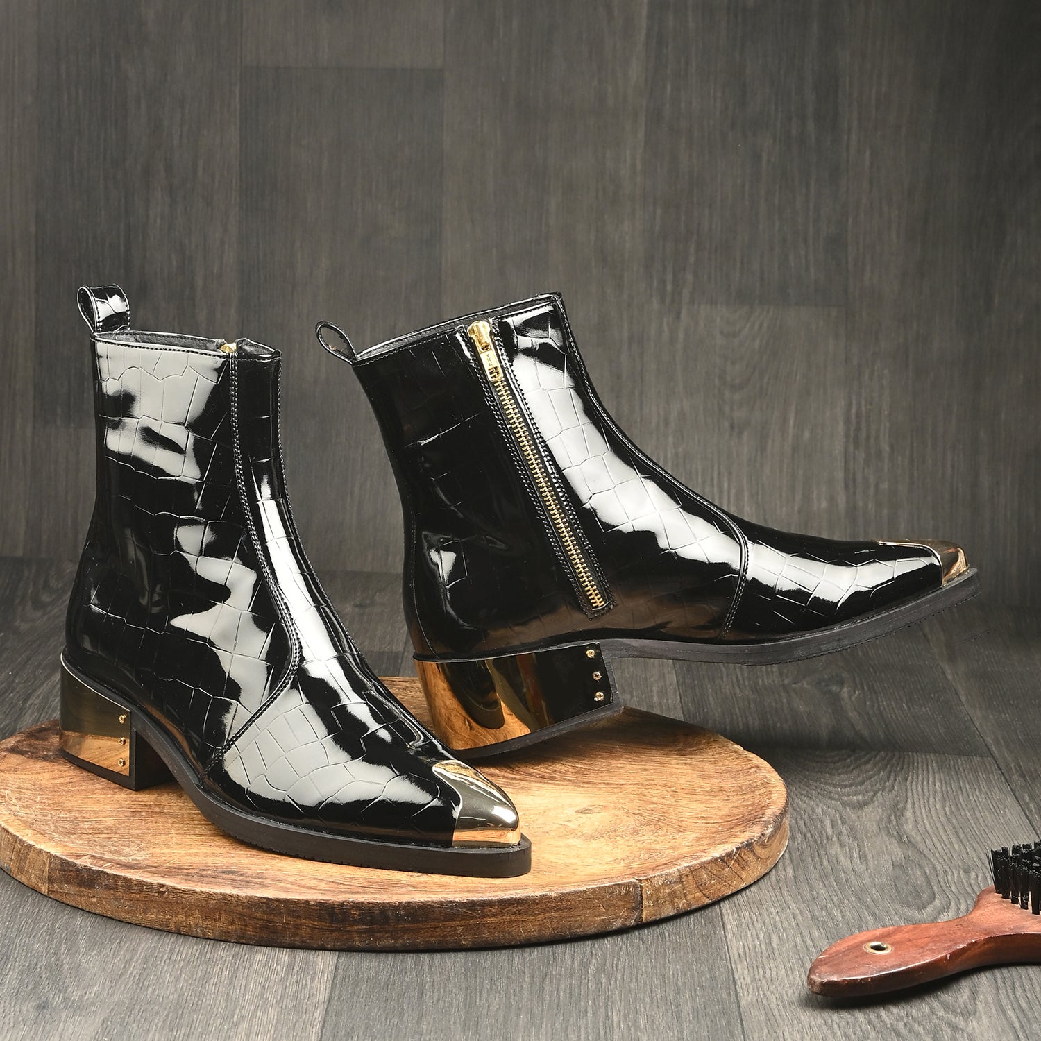 Black patent croc-embossed leather men’s ankle boots with gold toe cap, gold heel, and side zipper.