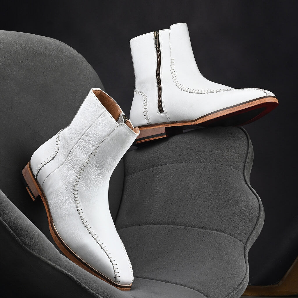 "Handcrafted white leather boots with intricate hand-stitching, a sturdy wooden sole, and a side zipper—blending bold style, comfort, and durability for versatile wear."






